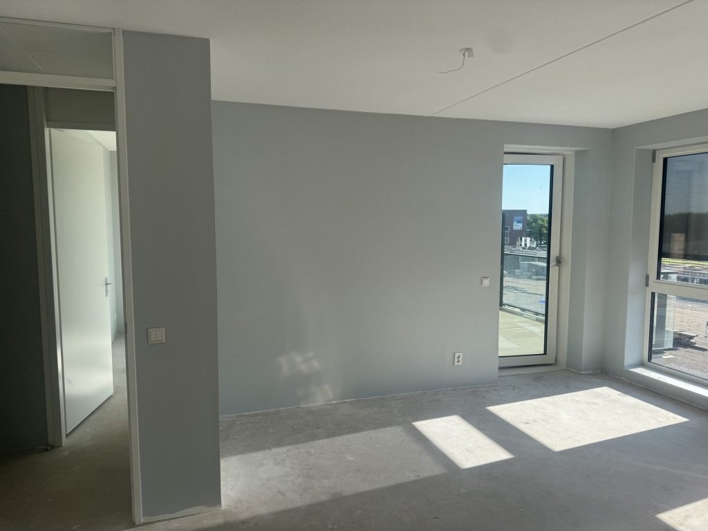 Lege nieuwbouwkamer met kale wanden en een betonvloer, klaar voor de afwerking
